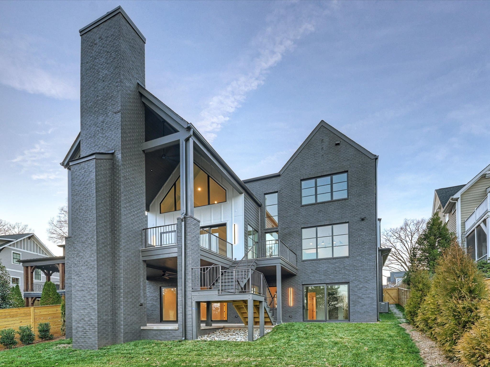Lorna rear elevation at dusk — three-story custom home with full-height brick chimney, Charlotte NC