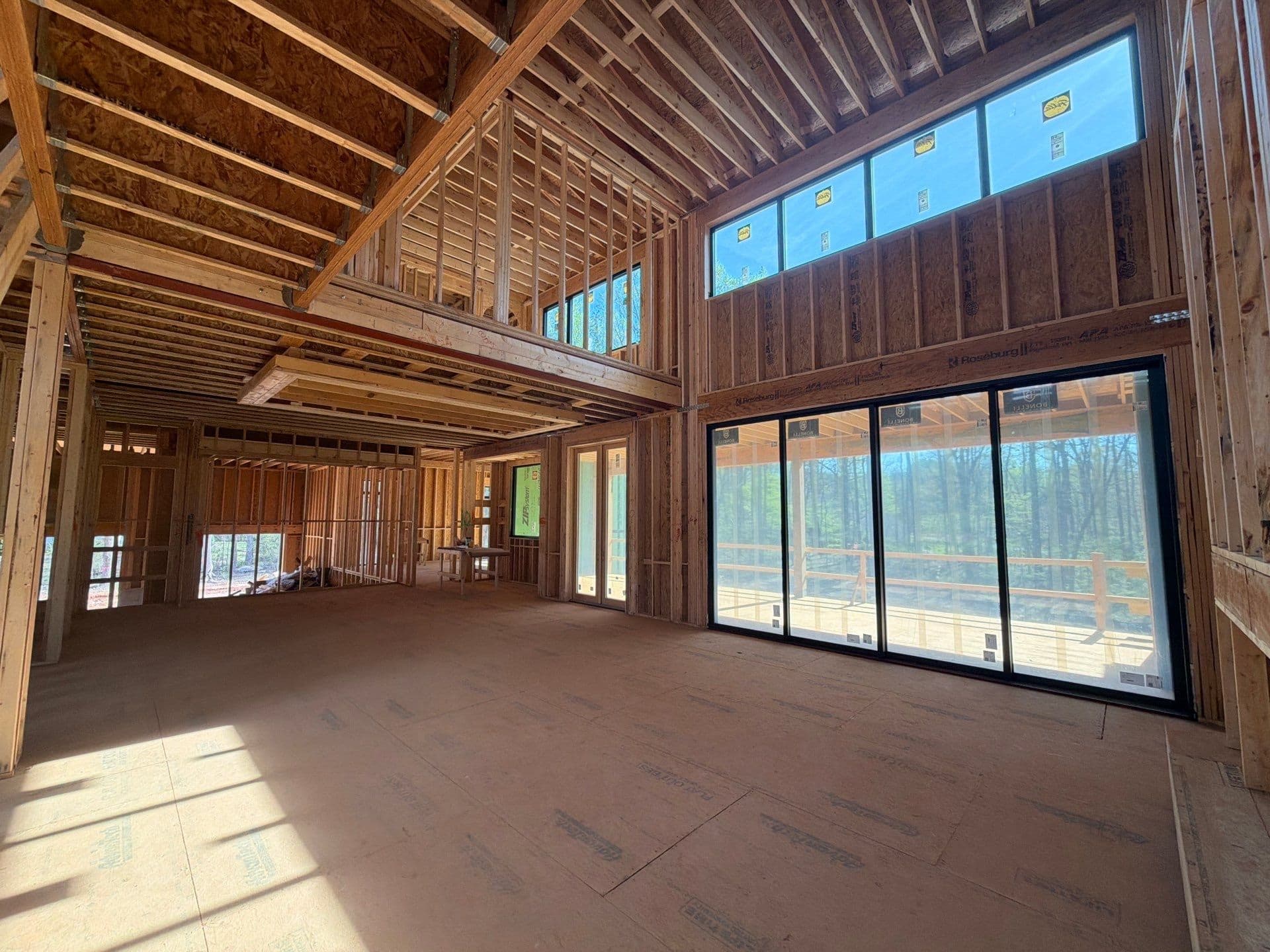 1107 Vision Path double-height living space with broad windows and an open upper landing during construction, Concord NC