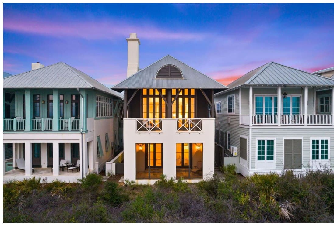 Inspiration imagery for The Preserve — a row of shingled, metal-roofed coastal homes at dusk, windows glowing